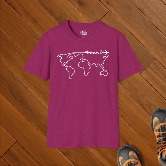 Heather magenta t-shirt featuring a minimalist white line art world map with the word “travel” and an airplane graphic flying across the top. Shirt is laid flat on wooden floor with hiking shoes visible.
