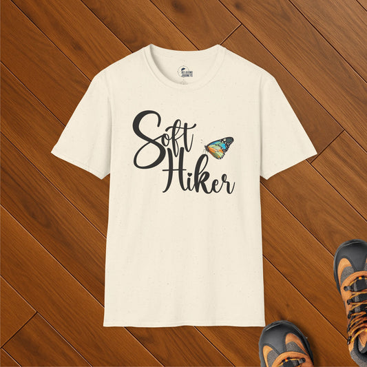 Cream speckled t-shirt with Soft Hiker script text and colorful butterfly graphic, styled on wood floor with hiking boots