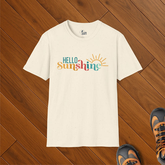 Cream speckled t-shirt with colorful “Hello Sunshine” text in teal, mustard, red, and turquoise, featuring a sun graphic, evoking cheerful ocean vibes.