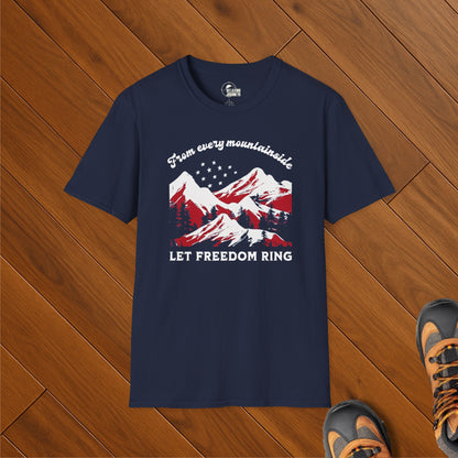 Navy blue t-shirt with red, white, and blue mountain design and the text “From every mountainside, Let Freedom Ring,” styled on wood floor with hiking boots