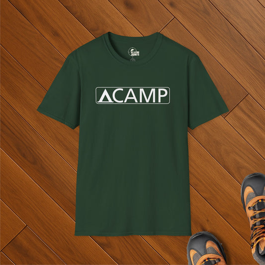 Forest green t-shirt with white CAMP text and national park-style triangle tent icon, laid on wood floor with hiking boots