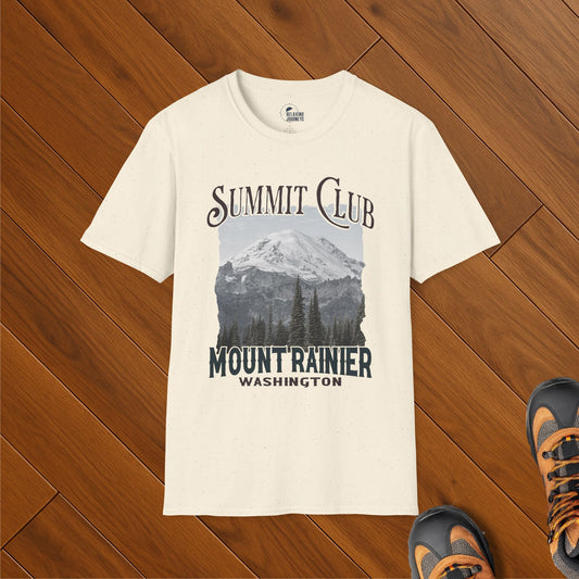 Cream speckled t-shirt featuring a vintage-style graphic of Mount Rainier in Washington with the text “Summit Club – Mount Rainier – Washington.” Shirt is laid flat on wooden floor with hiking shoes nearby.